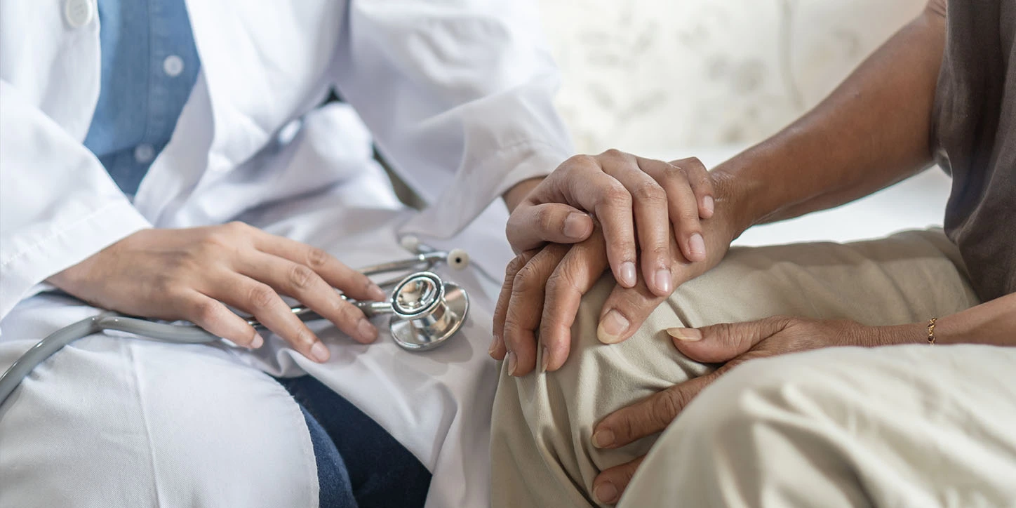 médica segurando amão de um paciente explicando como é feita a cirurgia de parkinson