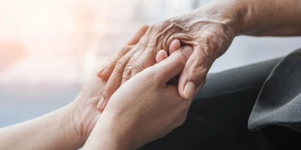 Duas mãos dadas, simbolizando o acolhimento com os sintomas não motores do parkinson